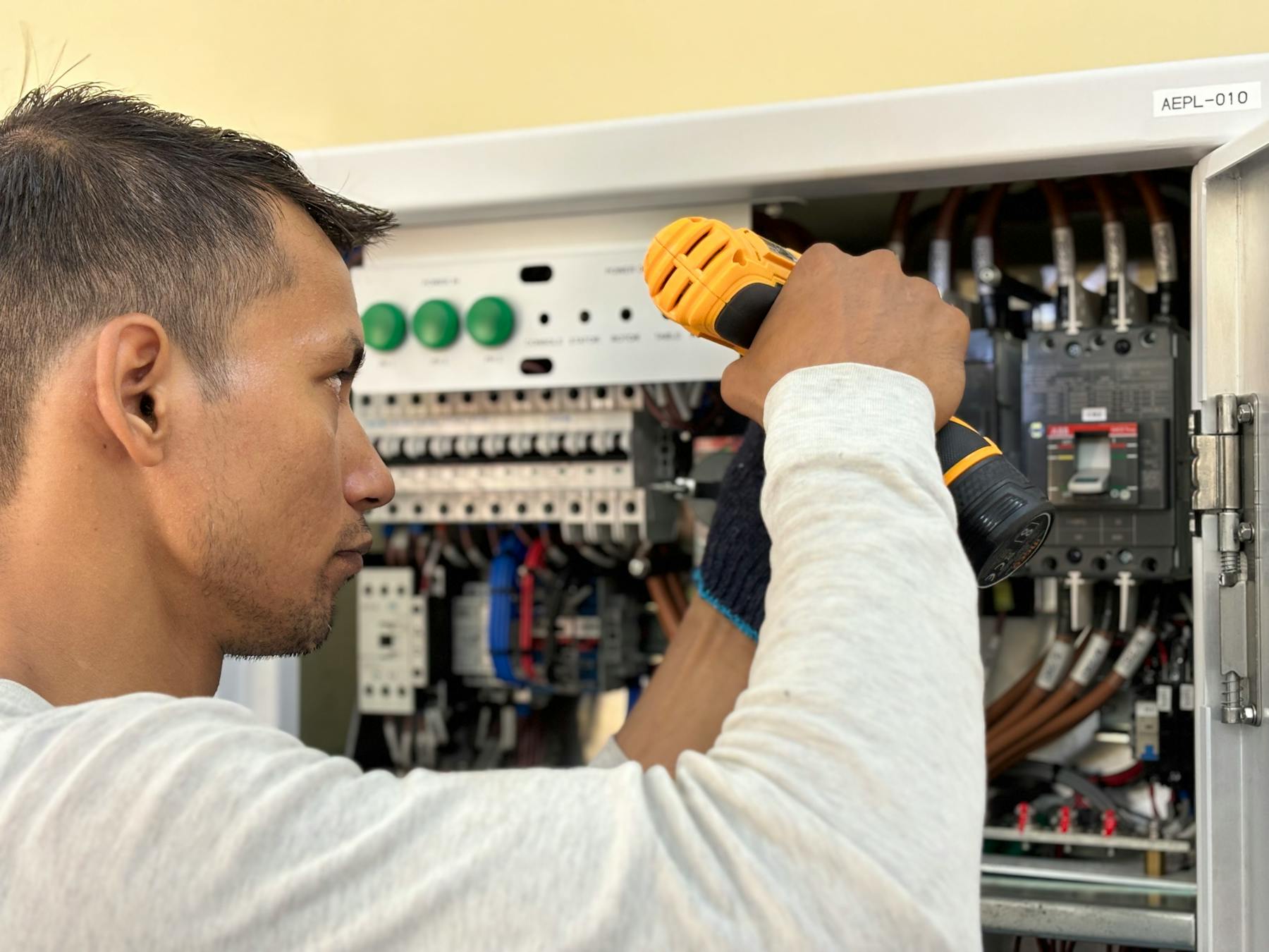 Technician with drill working on an electrical panel